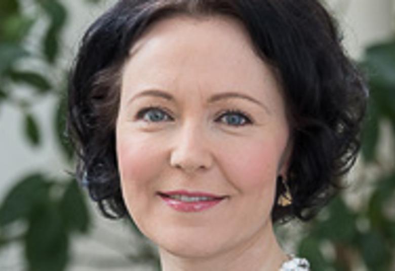 Kuvassa on Jenni Haukio kasvokuvassa.  Hänellä on tummat hiukset.