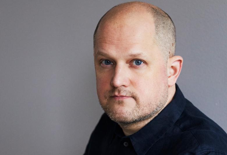 Kuvassa on Silja Kejonen istumassa sivuttain ja katsoo kameraan. Hänellä on musta-valkokuvioinen mekko päällään. Tausta on harmaa.