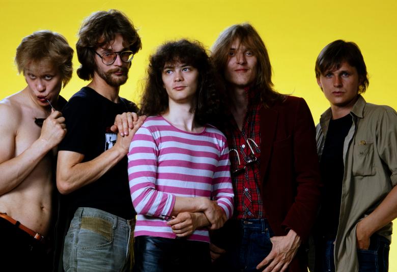 Kuvassa ovat Eppu Normaalin viisi jäsentä seisomassa.  Heistä vasemmalla olevalla Martti Syrjällä ei ole paitaa ja muilla on joko mustat tai keskimmäisellä valko-violetti t-paita.  Tausta on keltainen.