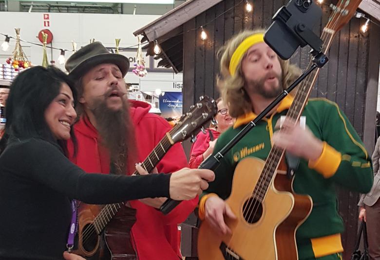 Kuvassa ovat Markus Pulkkinen ja Esko Vihava soittamassa kitaraa.  Heitä kuvaa kännykkäkepillä tummahiuksinen nainen.