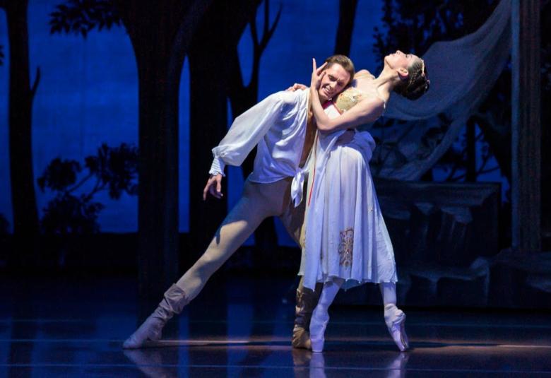 Kuvassa on vasemmalla Patrik Holeček valkoisessa paidassa ja vaalean ruskeissa sukkahousuissa. Hän nojaa valkoisessa puvussa sivuttain olevaan Romina Contrerasiin. Taustalla on sinimustaa metsäkulissia. 