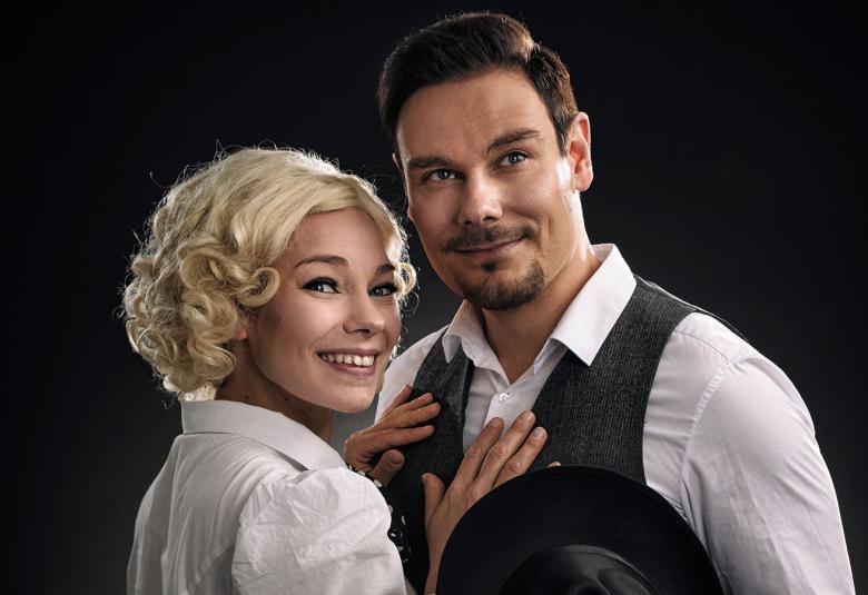 Kuvassa ovat Eeva Saarenpää ja Tommi Soidinmäki toistensa vieressä puolivartalokuvassa. Saarenpäällä on vaaleat kiharat hiukset ja valkoinen pusero.  Soidinmäellä on päällään harmaa liivi ja valkoinen paita.