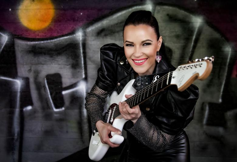 Kuvassa on Erja Lyytinen puolivartalokuvassa.  Hänellä valkoinen kitara edessään ja hän osoittaa sillä eteenpäin.  Taustalla on mustia kirjaimia narussa.  Ylhäällä on keltainen kuu.