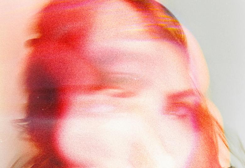 Kuvassa on taustalla on kasvojen muotoa ja ne on värjätty punaiseksi ja valkoiseksi. Tausta on vaaleaa oranssia  ja vaalean sinistä. Osa kirjan kannesta.