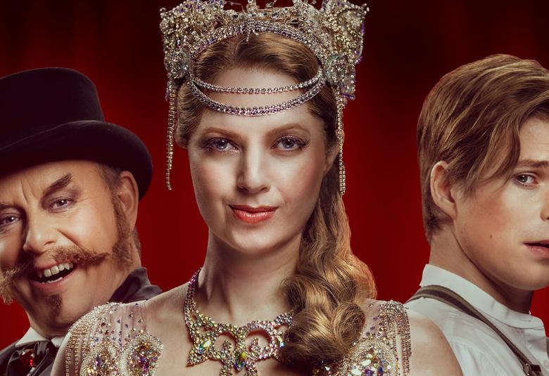 Kuvassa on Risto Kaskilahti kasvokuvassa vasemmalla silinterihattu päässään. Keskellä edessä on Jennie Storbacka korkeassa kampauksessa ja päässään ruskea korkeskoriste ja päällään saman värinen kirjottu pusero.  Oikealla on vinottain Martti Manninen.