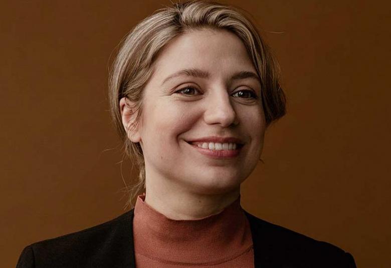 Kuvassa on on Dalia Stasevska puolivartalokuvassa. Hänellä on lyhyehköt vaalean ruskeat hiukset taakse kammattuna ja päällään ruskea poolo sekä musta jakku.  