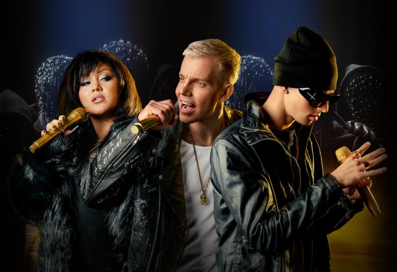 Kuvassa on vasemmalla nuori ruskea hiuksinen laulaja ruskea mikki kädessään.  Hänen vieressään on Elastinen, joka laulaa ja katse on vasemmalle. Hänellä on musta takki ja valkoinen t-paita. Oikealla vieressä on nuori mies, jolla on musta nahkatakki ja pipo. Hänen katseensa on alaspäin. Tausta on tumma.