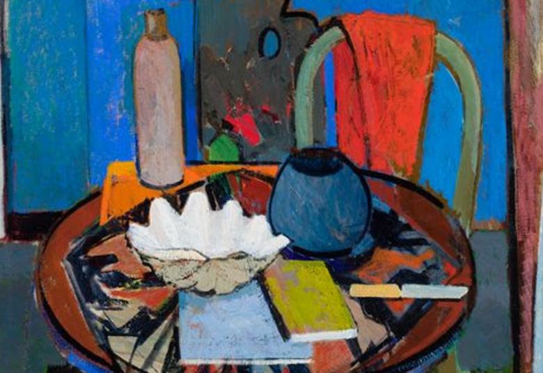 Kuvassa on ruskea pöytä, jossa muistiinpanolehtiöitä ja valkoinen iso simpukka sekä harmaa termospullo. Pöydän takana on  ruskean tuolin selkänoja. Taustalla on kirkasta sinistä ja sinivihreää.