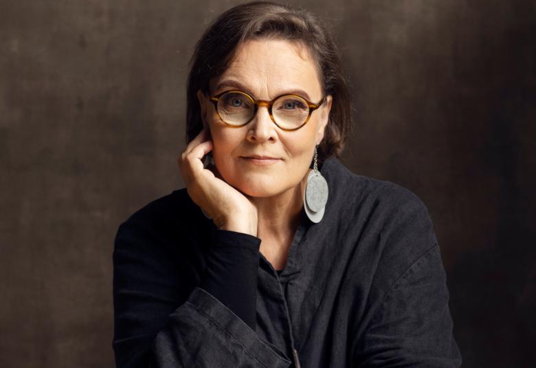 Kuvassa on Eppu Nuotio puolivartalokuvassa. Hänellä on tumma pusero ja hän nojaa hiukan oikealla kädellään poskeensa. 