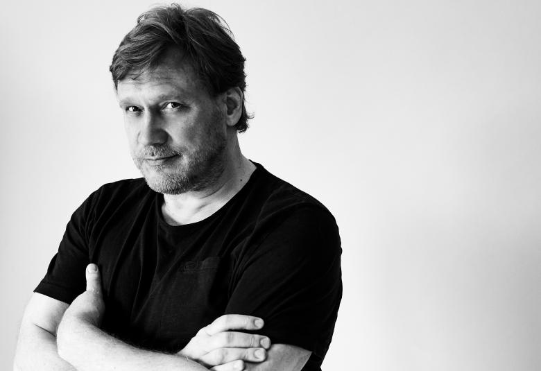 Kuvassa on Samuli Edelmann puolivartalokuvassa musta t-paita päällään. Hänellä on kädet ristissä rinnalla. Kuva on musta-valkoinen.
