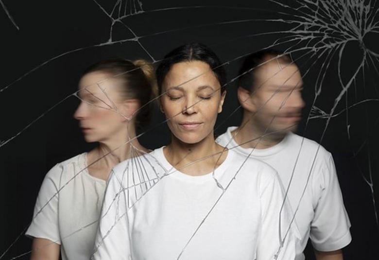 Kuvassa on keskellä yksi naisnäyttelijä ja vasemmalla toinen sivuttain.  Oikealla on miesnäyttelijä sivuttain. Kaikilla on valkoiset t-paidat ja he ovat silmät kiinni. Edessä on säröytynyt lasi. Tausta on tumma.