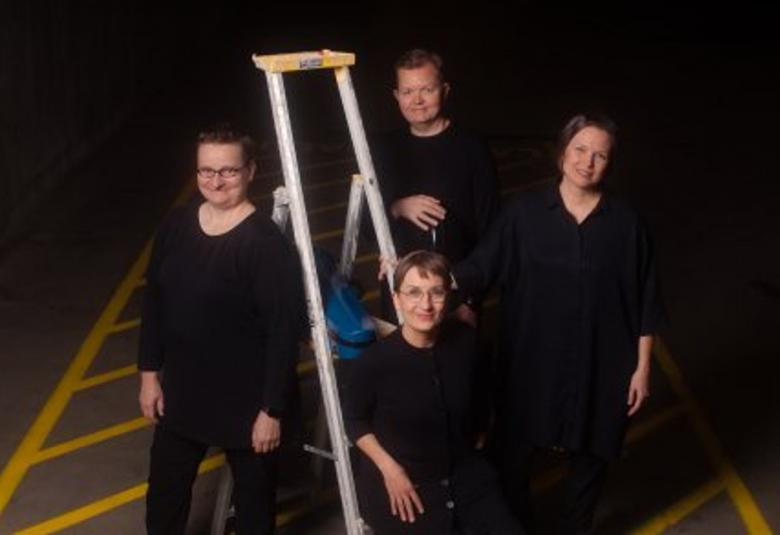 Kuvassa on Avanti-kvartettim ja he ovat tummalla tiellä, jossa on keltaista viivaa. Kaikki ovat mustissa vaatteissa ja keskellä on remonttitikkaat. Niiden vasemmalla puolella on yksi soittajista ja toinen istuu alimmalla portaalla.  Takana seisoo mies ja oikealla nainen. Tausta on tumma.