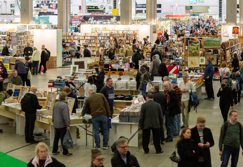 Kuvassa on Helsingin Kirjamessujen yleisöä kuvattuna ylhäältä päin ja siinä on ihmisiä kiertelemässä kirjapöytiä. 