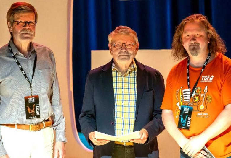 Kuvassa on vasemmalla Seppo Siirala vaalean harmaassa paidassa ja valkoisissa housuissa.  Keskellä on Arto Juusela tumman sinisessä takissa ja vaalean vihreässä paidassa sekä oikealla Tomi Tolvanen oranssissa t-paidassa.