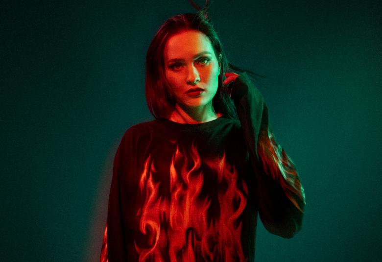 Kuvassa on keskellä SANNI tummassa punaisten liekkien puserossa. Tausta on tumma.