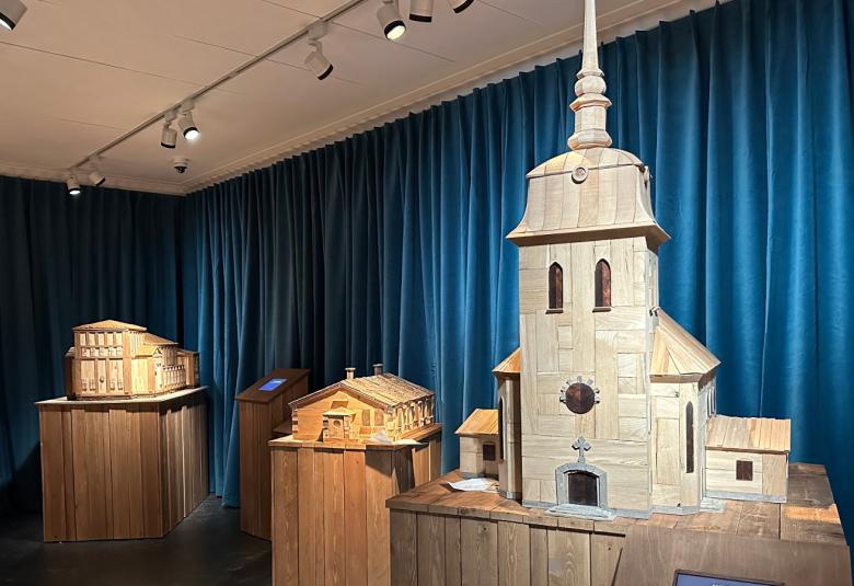 Kuvassa on siniverhoisessa näyttelytilassa puujalustojen päällä puisia pienoismalleja vanhoista rakennuksista. Oikealla etummaisena on Mäntän kirkko.