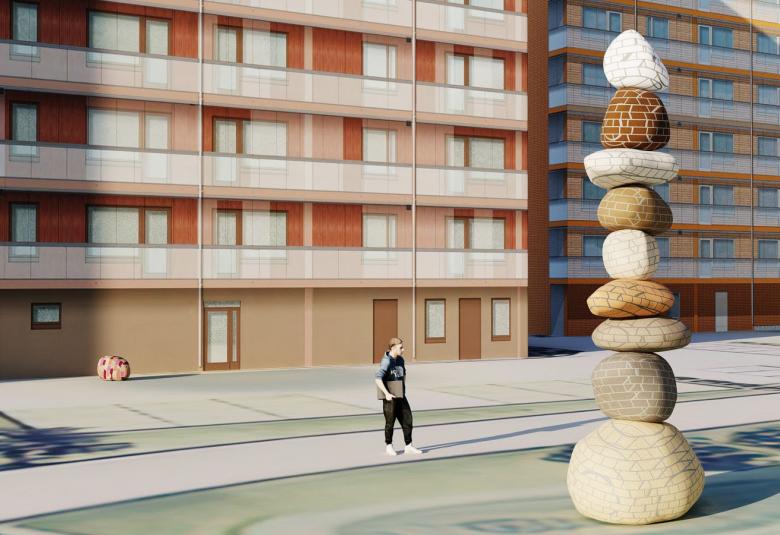 Kuvassa on taustalla valkoruskea kerrostalo, jossa on parvekerivit. Taustalla on toinen kerrostalo. Oikealla edessä on litteistä pyöreistä kivistä muodostuva monikerroksinen korkea patsas. Alhaalla on henkilö, joka on pieni suhteessa patsaaseen.