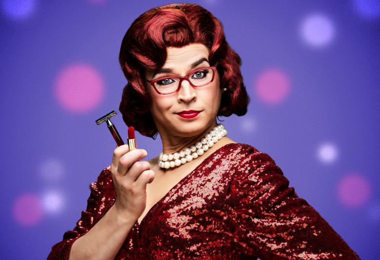 Kuvassa on Antti Lant Tootsiena puolivartalokuvassa. Hänellä on ruskea peruukki päässään ja ruskean kiiltävä mekko.  Oikeassa kädessä on huulipuna ja partaterä. Tausta on violetti ja siinä on pinkkejä palloja.