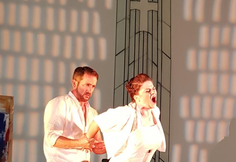 Kuvassa ovat Kevin Greenlaw pitelemässä kiinni Marjukka Tepposta, joka laulaa kärsivän näköisenä. Molemmilla ovat valkoiset asut.