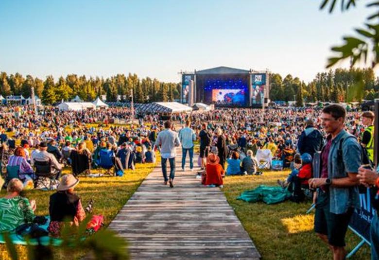 Kuvassa on takana Porin Kirjurinluodon esiintyjäteltta ja etualalla on yleisöä.  Keskellä on puulautapolkua.  Ilma on kesäinen ja on sininen taivas.