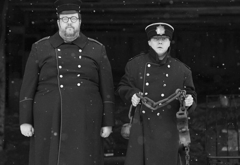 Kuvassa on kaksi vanhanajan poliisimiestä kaksirivinapitustakeissa ja koppalakeissa. Kuva on musta-valkoinen.