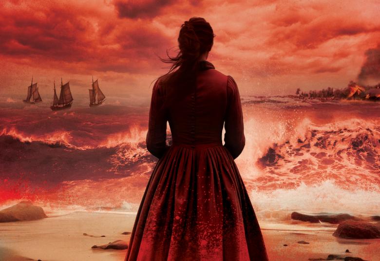 Kuvassa on taustalla punertavaa taivasta ja merta. Keskellä seisoo nainen selin tummassa mekossa ja katsoo merelle.