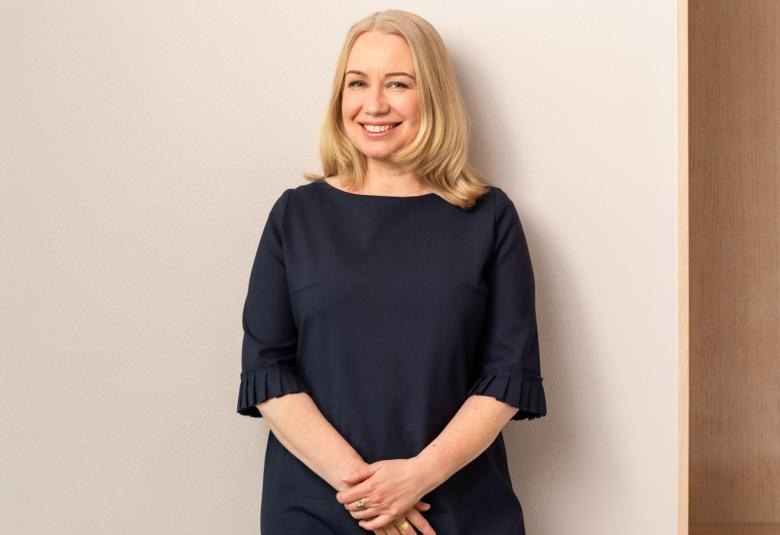 Kuvassa on Petra Havu seisomassa ja hänellä on musta mekko päällään. Hänellä on vaaleat, puolipitkät hiukset. Tausta on vaalea.