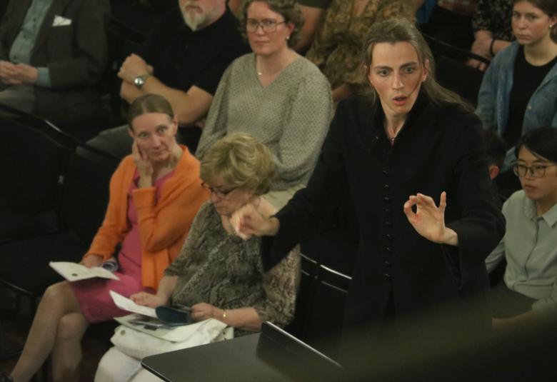 Kuvassa on mustaan pukeutunut Felix Benati johtamassa orkesteria oikealla ja vasemmalla alempana istuu tuomareita polven päällä arviointipapereita.  Taustalla näkyy yleisoä.