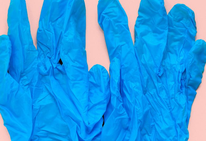 Kuvassa on vaalean roosalla pohjalla vaalean siniset ohuet muovihanskat.