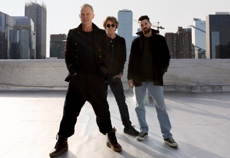 Kuvassa on Sting edessä mustissa vaatteissa ja hänen takanaan vierekkäin kaksi bändin jäsentä. Oikean puoleisella on vaalean siniset farkut. Taustalla näkyy korkeita kerrostaloja.