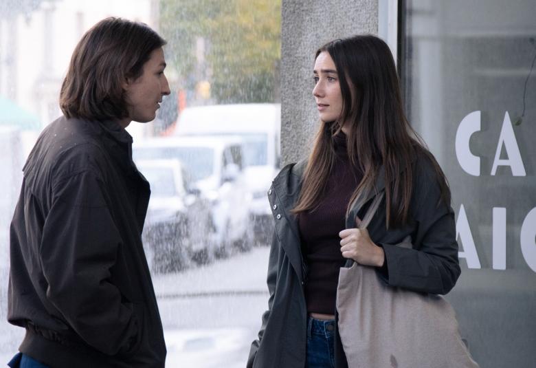 Kuvassa ovat kadun kulmassa Elias Westerberg tummissa vaatteissa  ja tummissa pitkissä hiuksissa sekä Linnea Leino myös tummissa vaatteissa. Taustalla näkyy vaaleasti autoja.