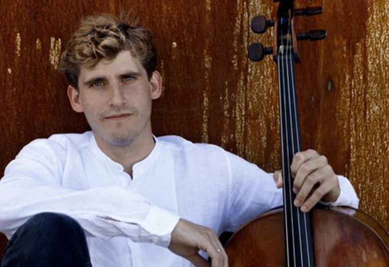 Kuvassa on Andreas Brantelid istumassa lattialla puolivartalokuvassa ja nojaamassa seinään. Hänellä on valkoien paita. Tausta on ruosteen punainen.