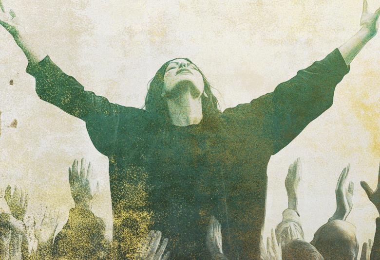 Kuvassa on nuori nainen mustassa leveässä vaatteessa kädet ja kasvot ylöspäin. Alapuolella on yleisöä kädet ylhäällä.  Kuvan sävy on vihertävä ja kuva on osa kirjan kannesta.