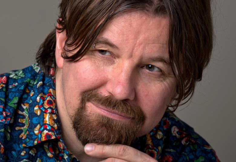 Kuvassa on Kari Kanala kasvokuvassa vinottain. Hänen etusormensa hipoo leukapartaa.