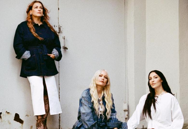 Kuvassa on Erin seisomassa vaaleaa risaista varaston ovea vasten.  Hänellä on musta takki ja valkoiset housut.  Alempana istuu Anna Puu sinisessä takissa ja vaaleissa pitkissä hiuksissa.  Hänen oikealla puolellaan on tumma hiuksinen Ida Paul valkosiessa puserossa.