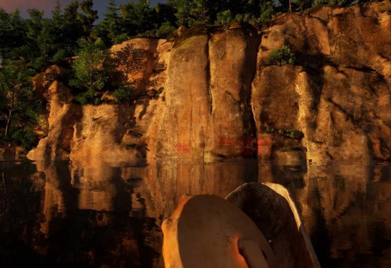 Kuvassa on kalliota ruskehtavassa iltavalaistuksessa. Etuoikealla on osa rummusta ja etualan järvi on tyyni ja heijastaa kalliota. Kallion päällä on mäntyjä. Kallion alareunassa näkyy punaisia kalliomaalauksia. 