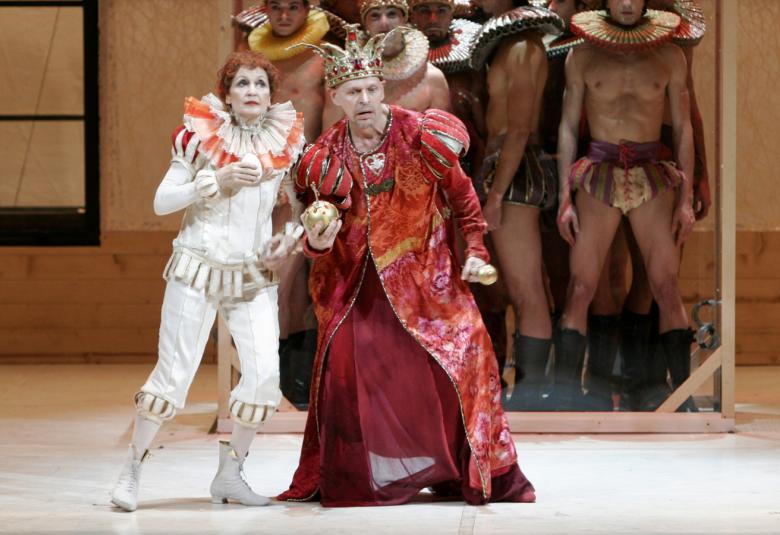 Kuvassa on vasemmalla valkoisessa fakiiripuvussa ja oikealla puolella on Jorma Uotinen hieman kumartuneena punaisessa pitkässä kaavussa.  Taustalla tiivinä ryhmänä vaalean ruskeissa sotilasasuisia miehiä.