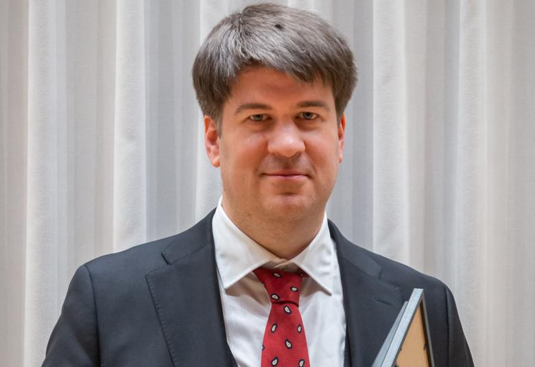 Kuvassa on sävellyskilpailun voittaja Matei Gheorghiu puolivartalokuvassa ja hänellä on kädessään kukat ja kunnakirja.