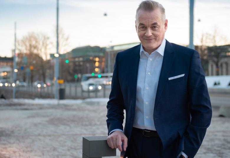 Kuvassa on Arto Nyberg seisomassa taustallaan epätarkasti kauempana Mannerheimintien rakennuksia. Nybergillä on päällään tumma puku ja valkoinen paita.