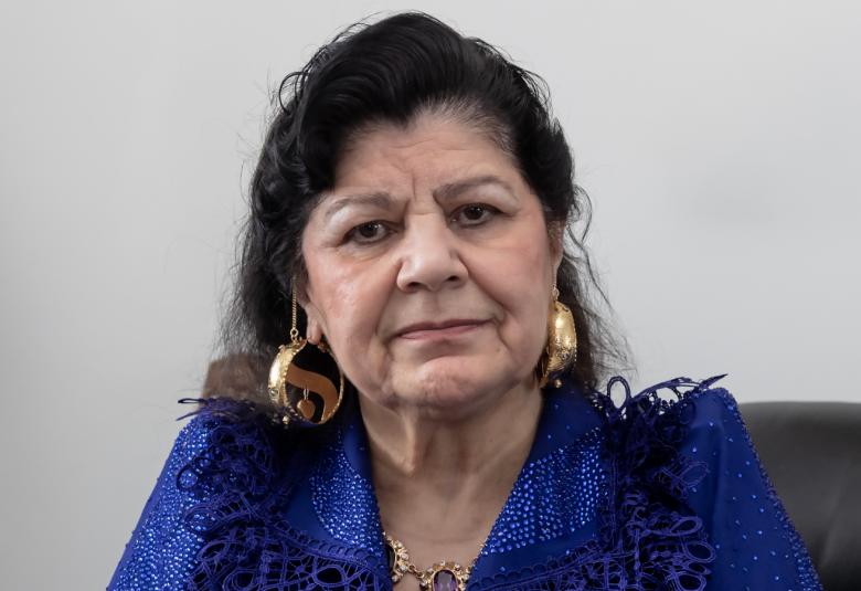 Kuvassa on Hilja Grönfors puolivartalokuvassa istumassa. Hänellä on tummat hiukset ja sininen pusero. Tausta on harmaa.