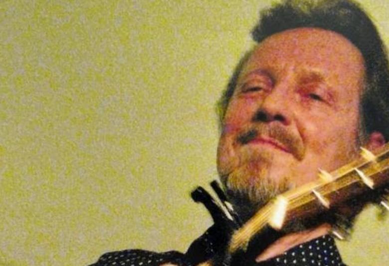 Kuvassa on Pave Maijanen kuvattuna alhaalta päin. Hän soittaa kitaraa ja tausta on vihertänän keltainen.