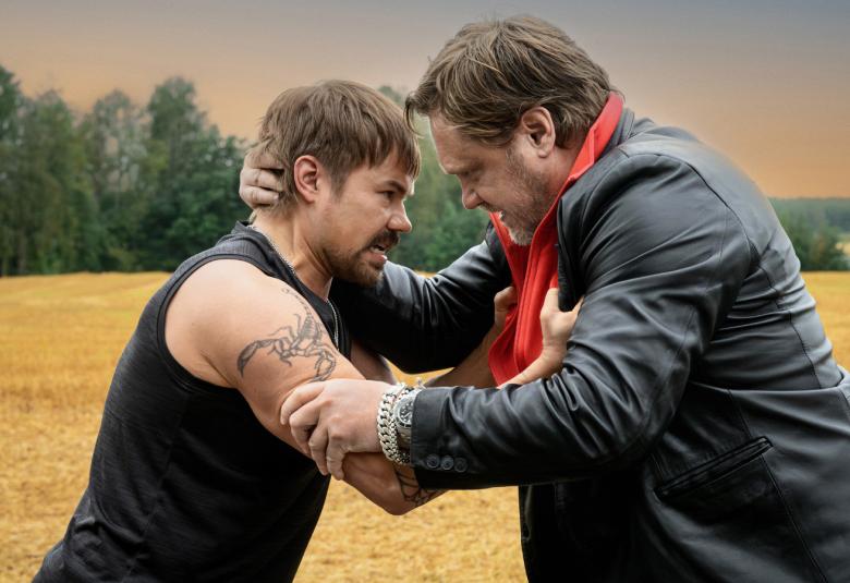 Kuvassa ovat päät vastakkain puskemassa vasemmalla Joel Hirvonen ja oikealla amuli Edelmann. Taustalla on peltomaisemaa, jossa on keltaista viljapeltoa.