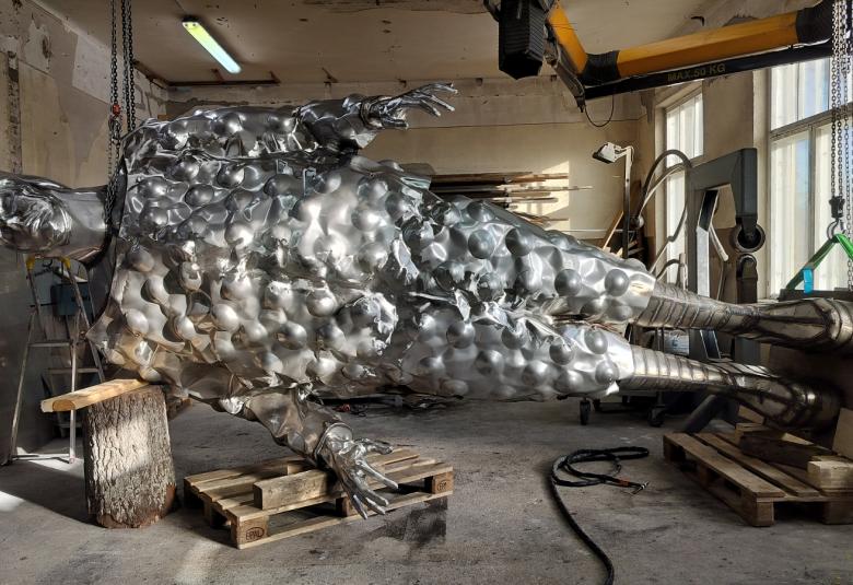 Kuvassa on teräksinen miestä esittävä suuri veistos työhuoneella poikittain ja ympärillä on työhuonetta.