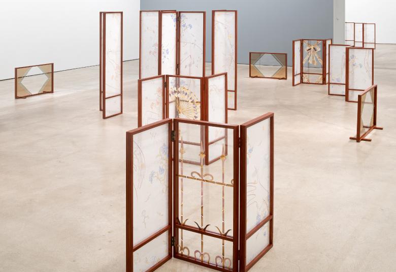 Kuvassa on useita ruskeapuitteisia läpinäkyviä sermejä.  Sermeissä on himmeitä kuviointeja.  Tila on vaalea.