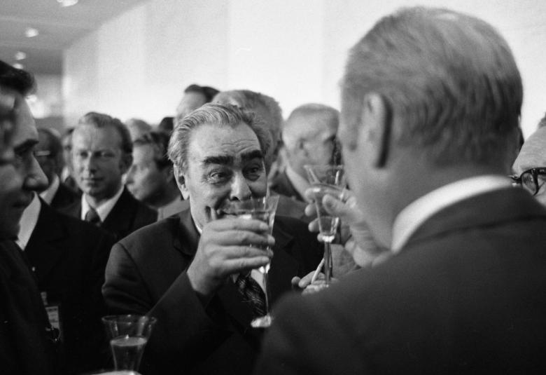 Kuvassa on coktail-tilaisuus, jossa keskellä on Leonid Brezhnev nostamassa maljaa ja häntä vastapäätä seisoo selin Gerald ford.  Kuvan helnkilöt ovat puolivartalokuvassa.