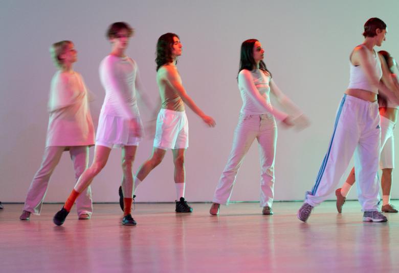 Kuvassa ovat kuusi tanssijaa rivissä tanssiasennossa ja kuvan sävy on pastellinen vaalean violetti tai harmahtava. Tanssijoilla on vaaleat, erilaiset harjoitusmaiset asut päällään.  