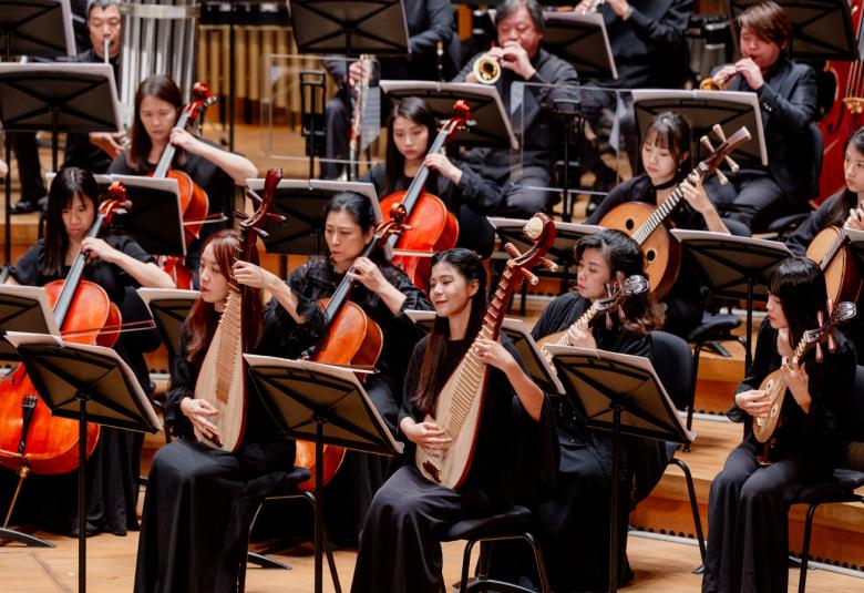Kuvassa on Kaohsiung Traditional Orchestra ja siinä on etualalla vinottain näissoittajia heidän traditionaalisen soittimensa kanssa mustissa mekoissa.