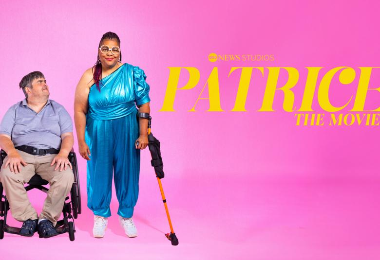 Kuvassa on pinkillä taustalla vasemmalla istumassa mies tuolilla vaalean sinisessä paidassa ja vaalean ruskeat housut.  Hänen vieressään seisoo nainen tummaihoinen nainen. Hänellä on pitkät tummat hiukset ja turkoosi, yhtenäinen housupuku sekä vasemmalla kyynertuki. 