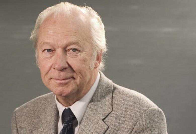 Kuvassa on Aulis Sallinen puolivartalokuvassa. Hänellä on harmahtava takki, valkoinen kauluspaita ja pumma kravatti.  Tausta on harmaa.