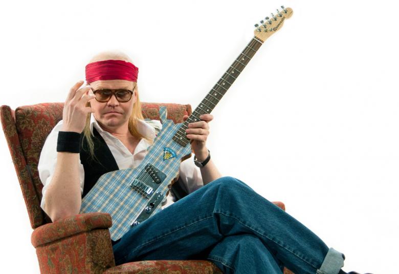 Kuvassa on Otto Kanerva Juicena ja hän istuu rennosti nojatuolissa kitara pystyssä oikealla. Vasen käsi on pystyssä. Hänellä on punainen nauha otsan päällä ja valkoinen paita, musta nauha ja farkut. Tausta on valkoinen.